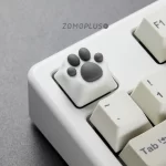 White-grey ZOMOPLUS kitty paw keycap shown from a side angle, installed on a keyboard, combining cute design with a high-quality typing experience.